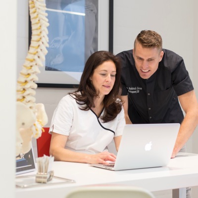 Osteopaat Lieven Van Reybrouck kijkt samen met de chiropractor Vicky Verhulst (zijn echtgenote) naar de laptop.