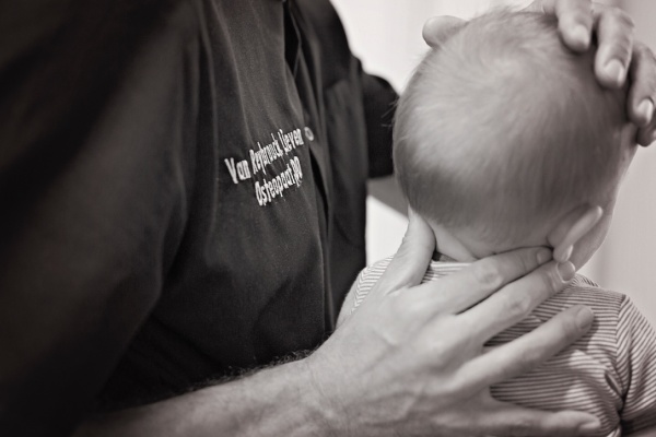 Osteopaat Lieven Van Reybrouck behandelt een baby'tje haar nekje in zit.